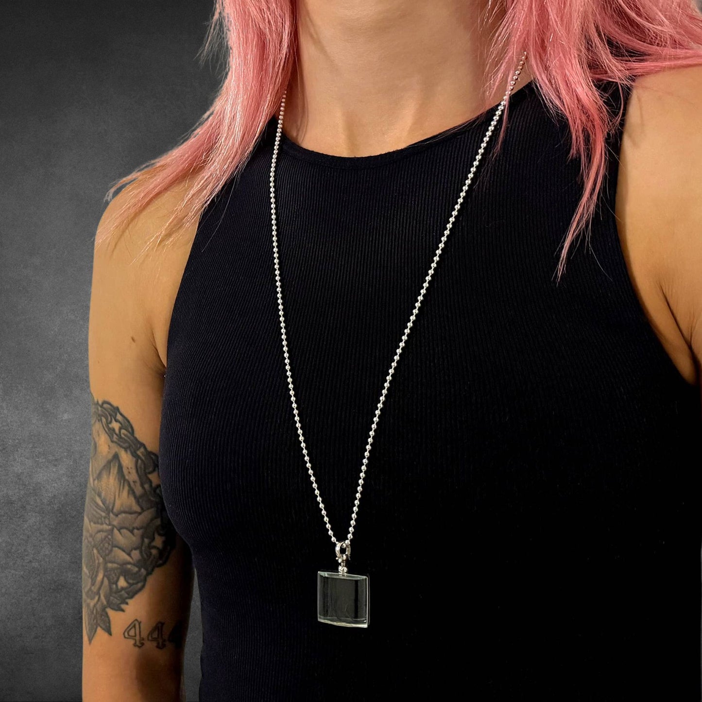 ASHES OF HIS HOODIE pendant on 28 inch high-shine ball chain worn by tattooed female model on grey background