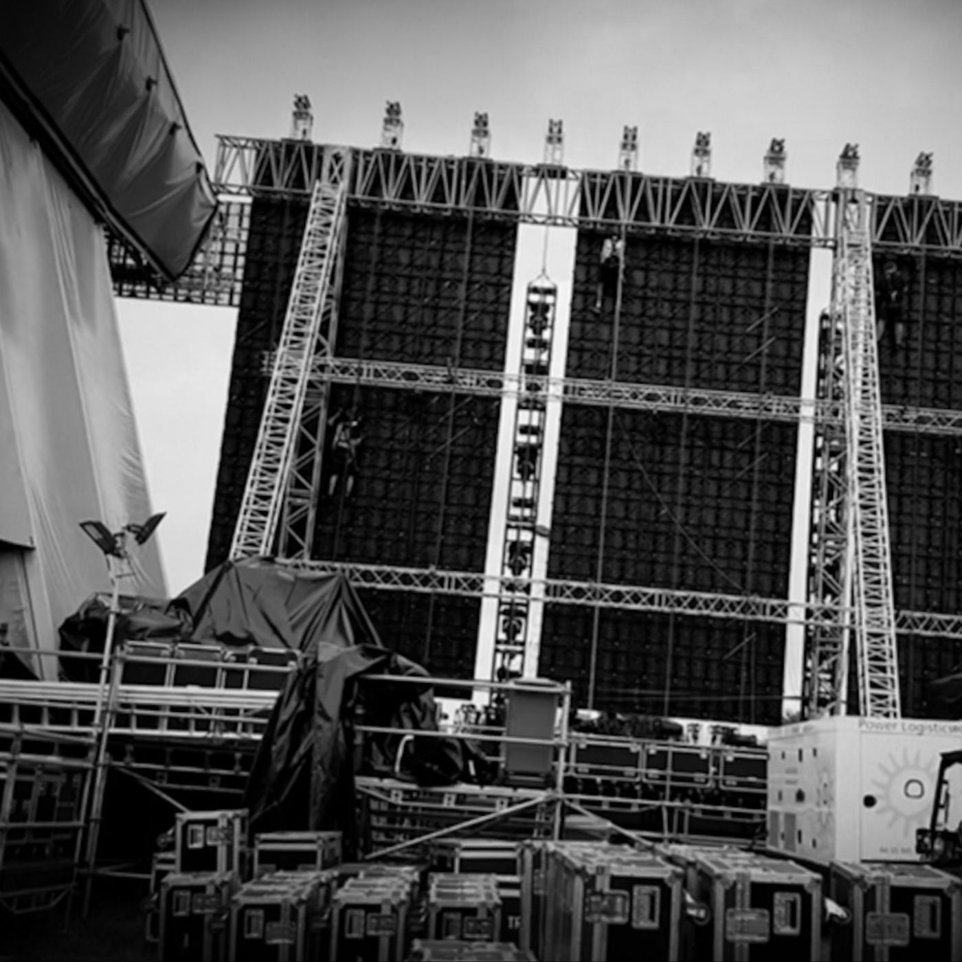 Back stage area at a large outdoor festival with scaffolding and flight cases. 