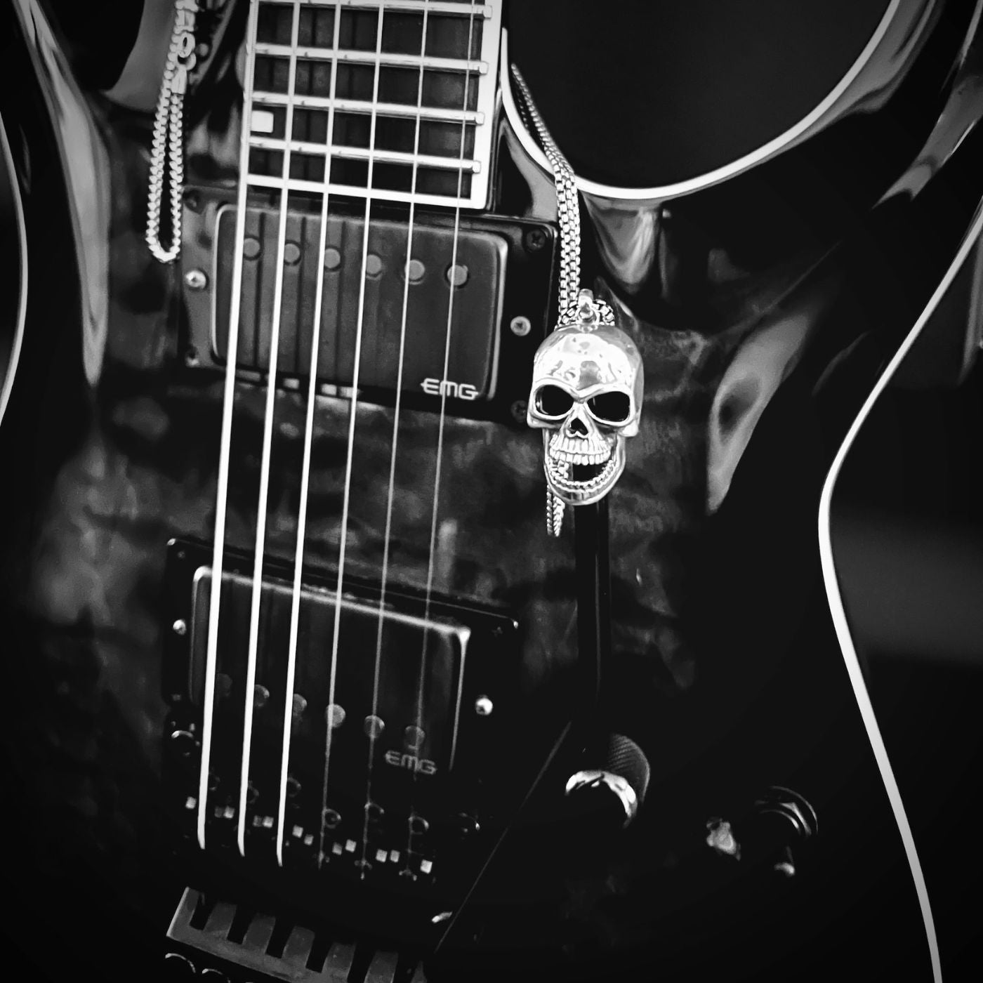 FINAL LAUGH sterling silver skull pendant necklace on a black ESP electric guitar under stage lighting.