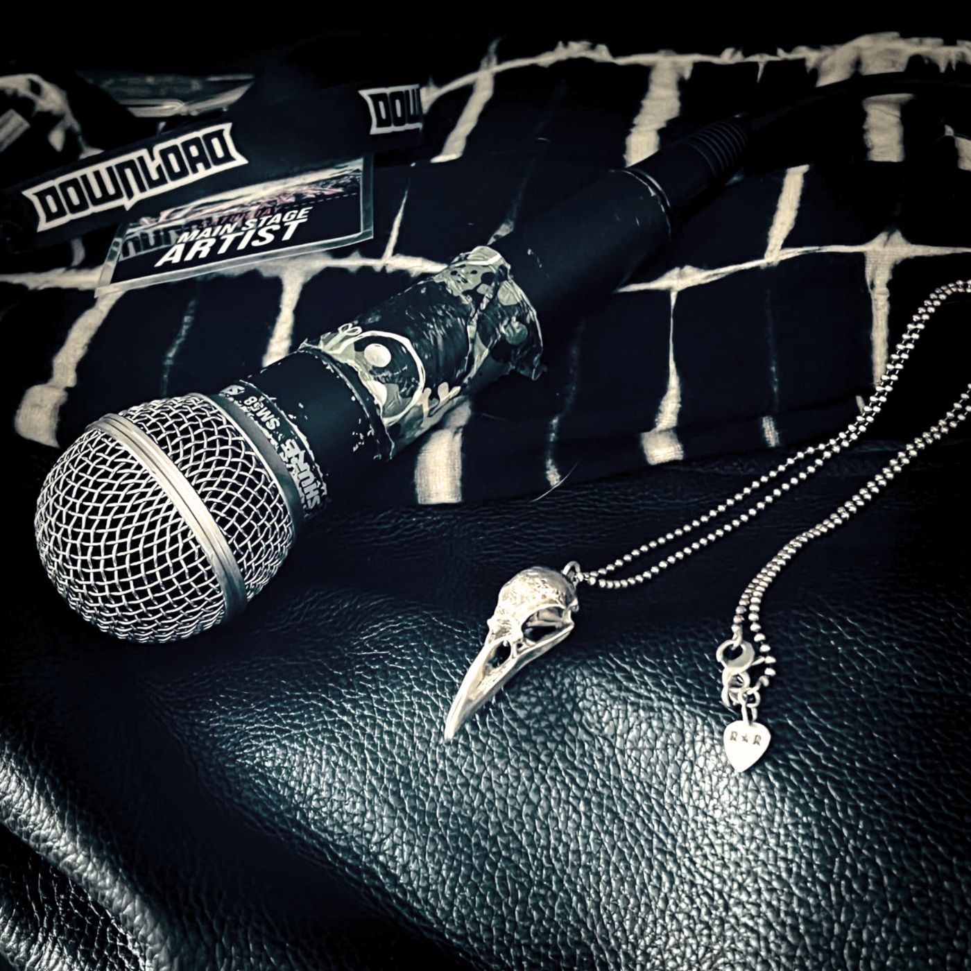 CROW'D CONTROL sterling silver pendant and ball chain styled beside a microphone backstage at a live music event.