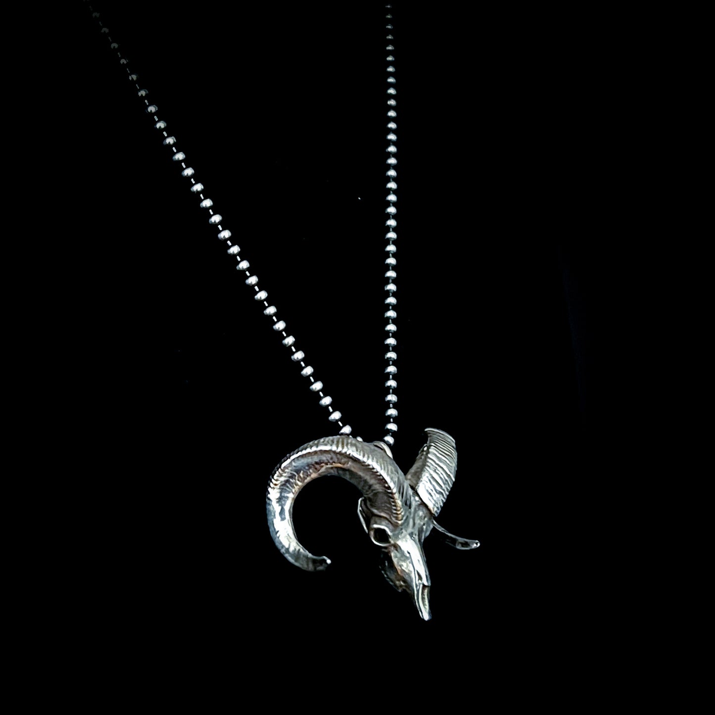 Sterling silver bighorn sheep skull pendant called Born to Headbang, shown from the side on a 24-inch ball chain