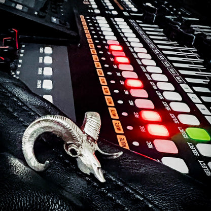 Sterling silver bighorn sheep skull pendant from ROCKSTAR★REFINEMENTS
styled on a recording desk with mixer faders, and glowing recording ights.
