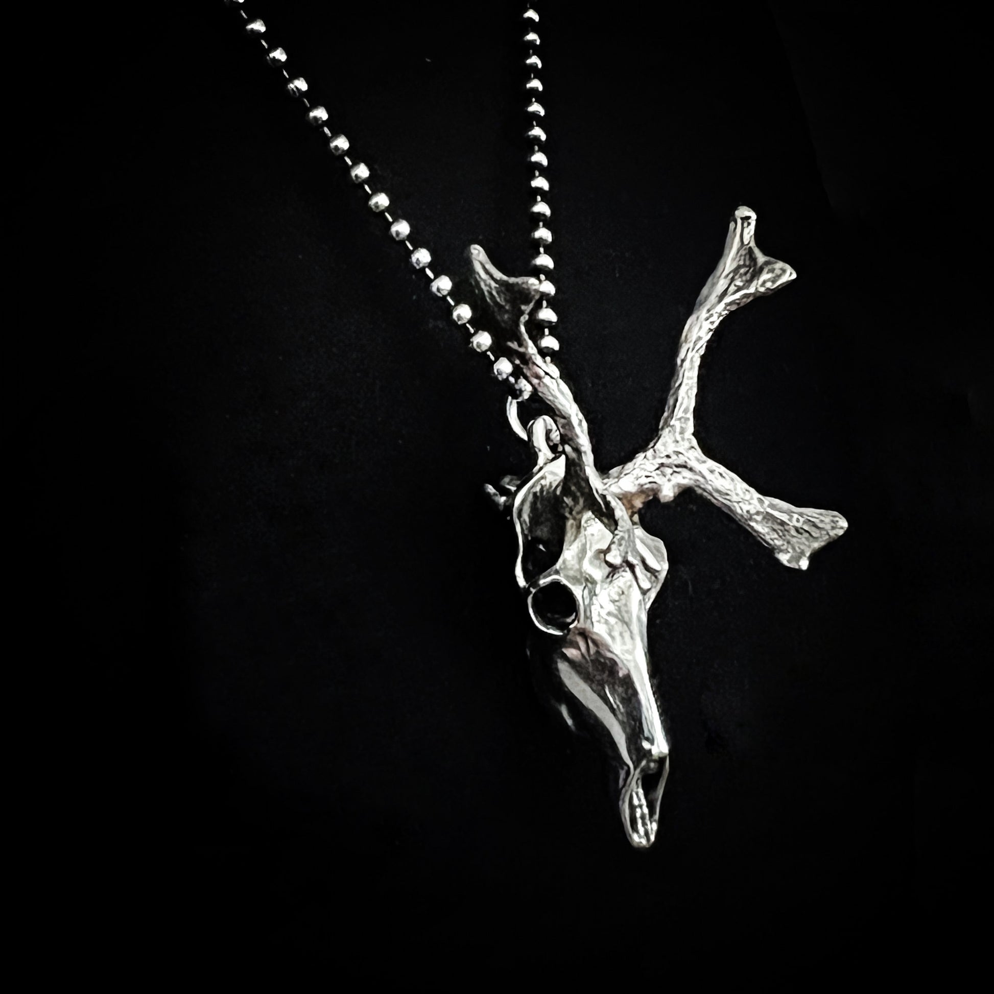 Sterling silver reindeer pendant on oxidised ball chain on a black background