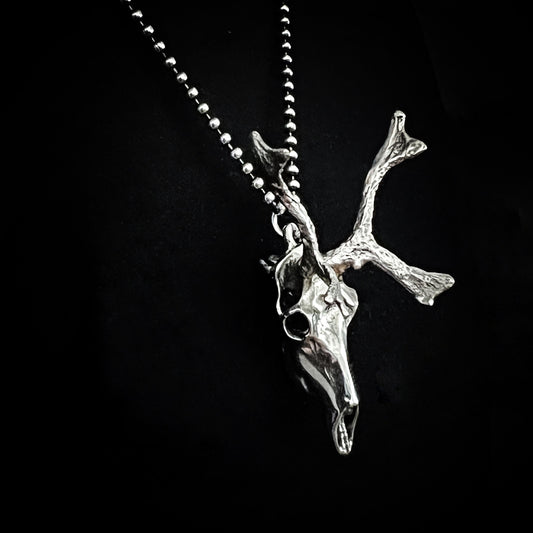 Sterling silver reindeer pendant on oxidised ball chain on a black background