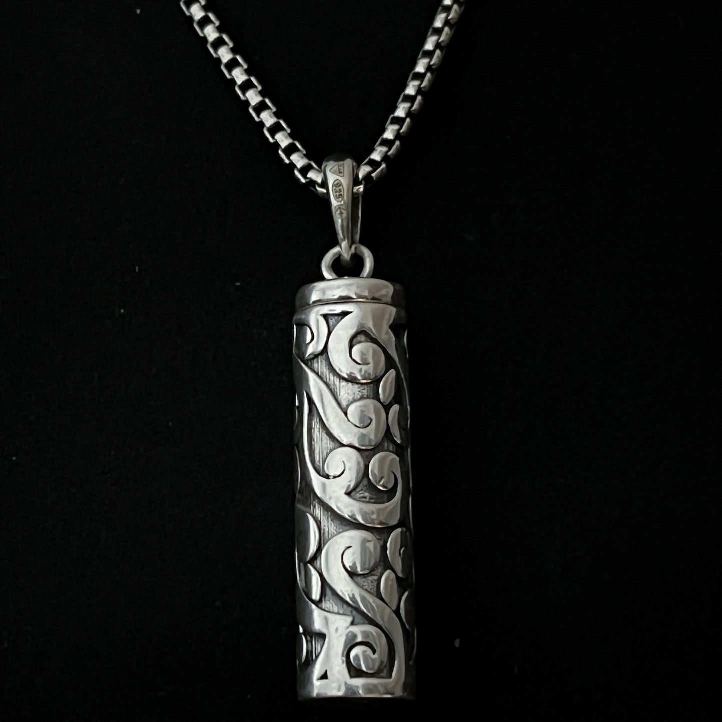 Sterling silver POISON IS THE CURE locket pendant on oxidised solid silver box chain. Photographed close up. 