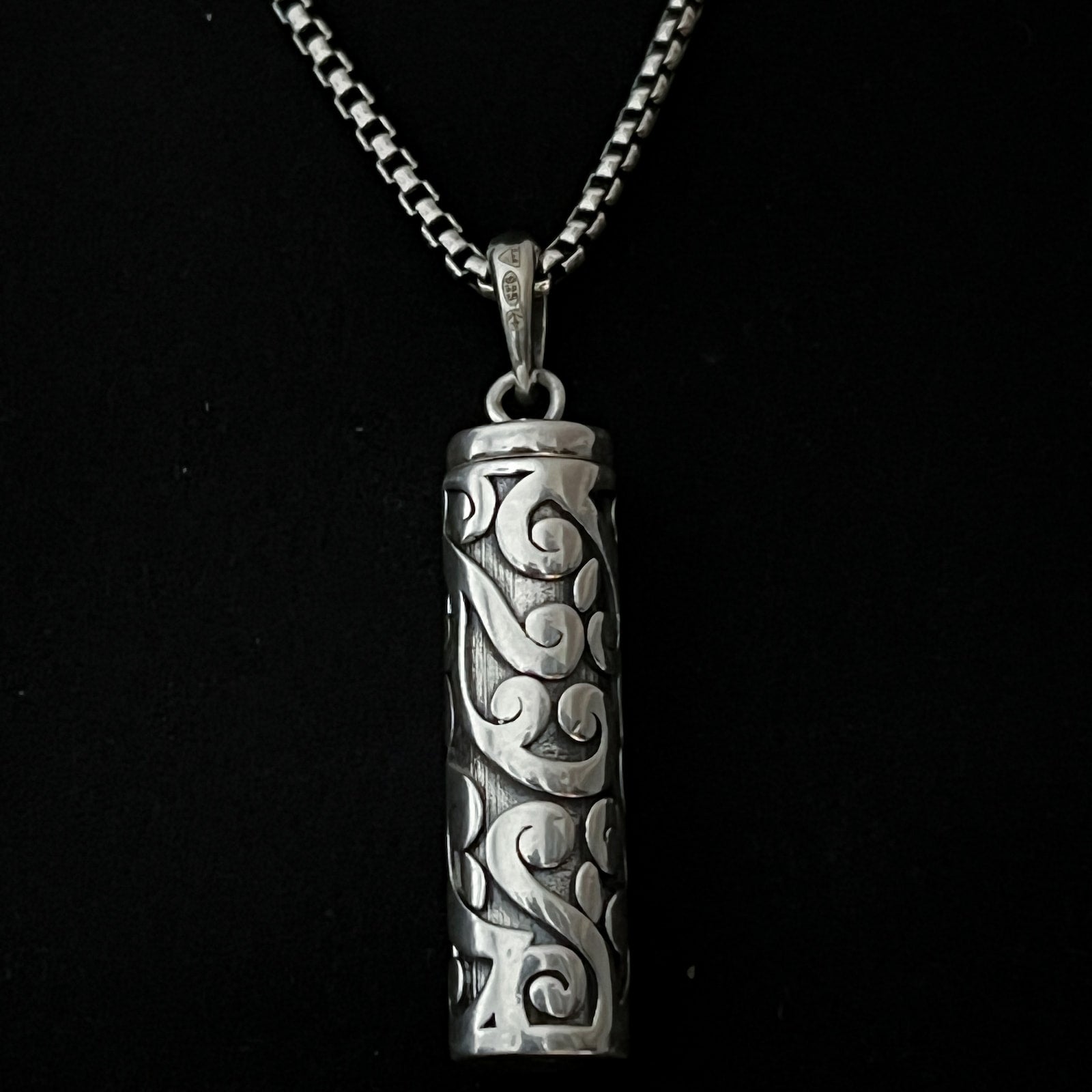 Sterling silver POISON IS THE CURE locket pendant on oxidised solid silver box chain. Photographed close up. 