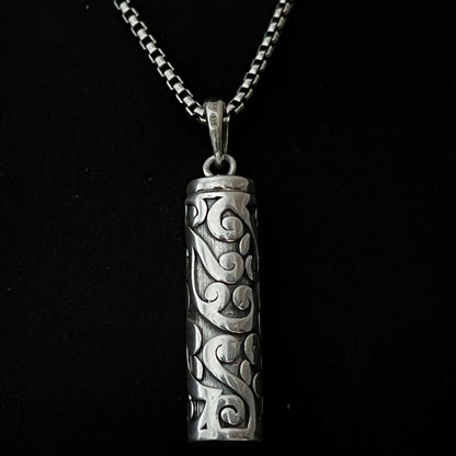Sterling silver POISON IS THE CURE locket pendant on oxidised solid silver box chain. Photographed close up. 