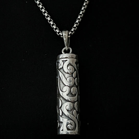 Sterling silver POISON IS THE CURE locket pendant on oxidised solid silver box chain. Photographed close up. 