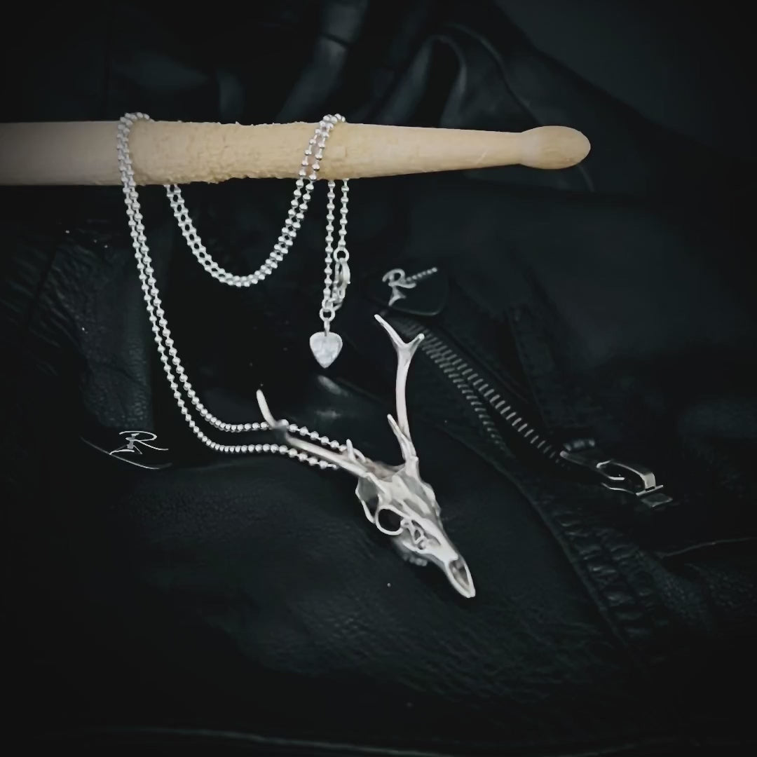 Sterling silver FAWN OF THE DEAD pendant with the chain draped over a drumstick and and the R★R jewellery tag gently swinging.