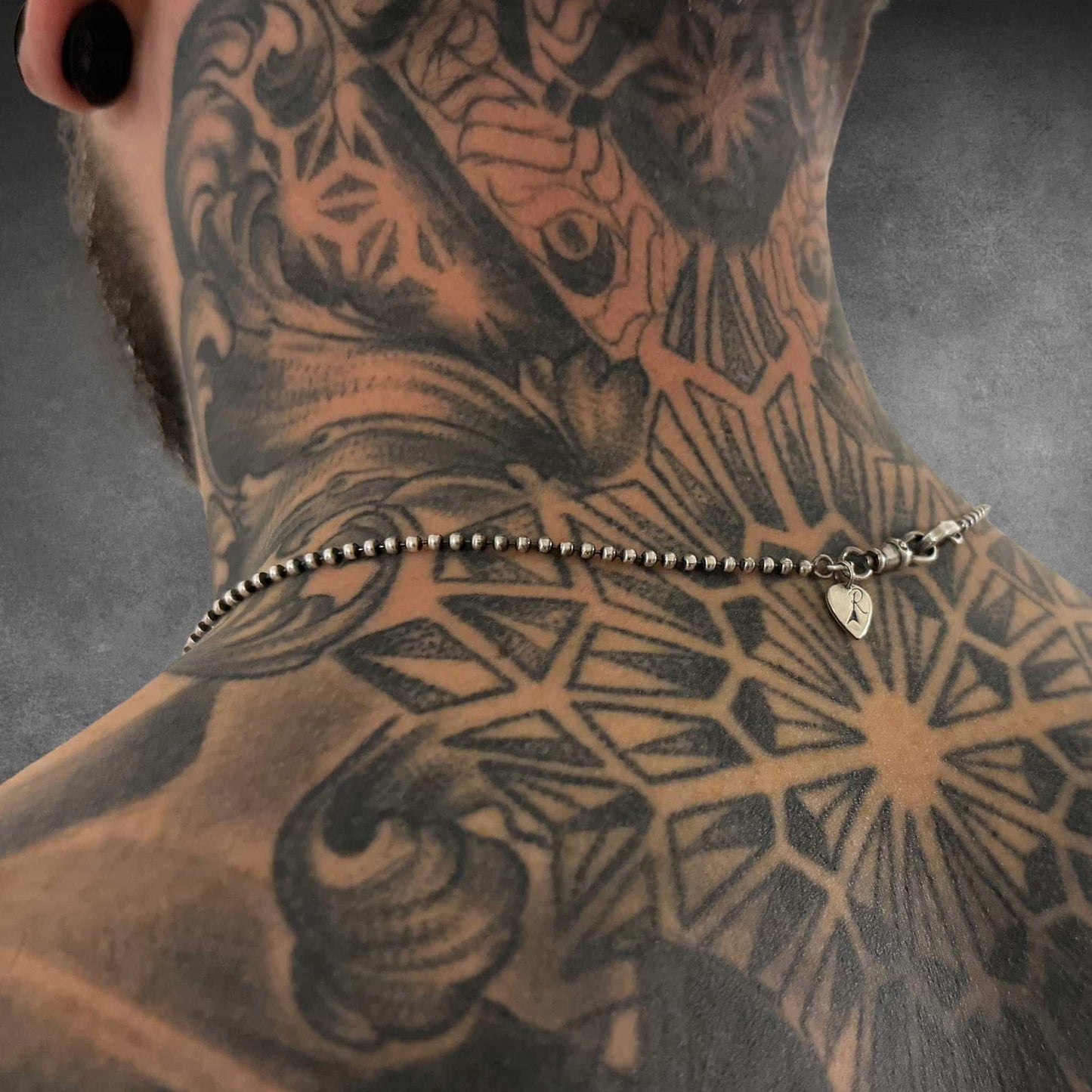 Rear view of 2.5mm ball chain showing clasp detail worn by tattooed male model.