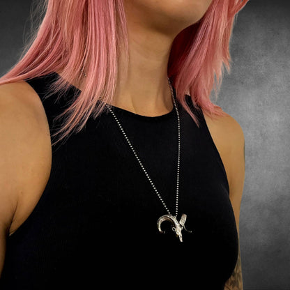 BORN TO HEADBANG ram pendant on 24 inch ball chain on female model, photographed on grey backrop