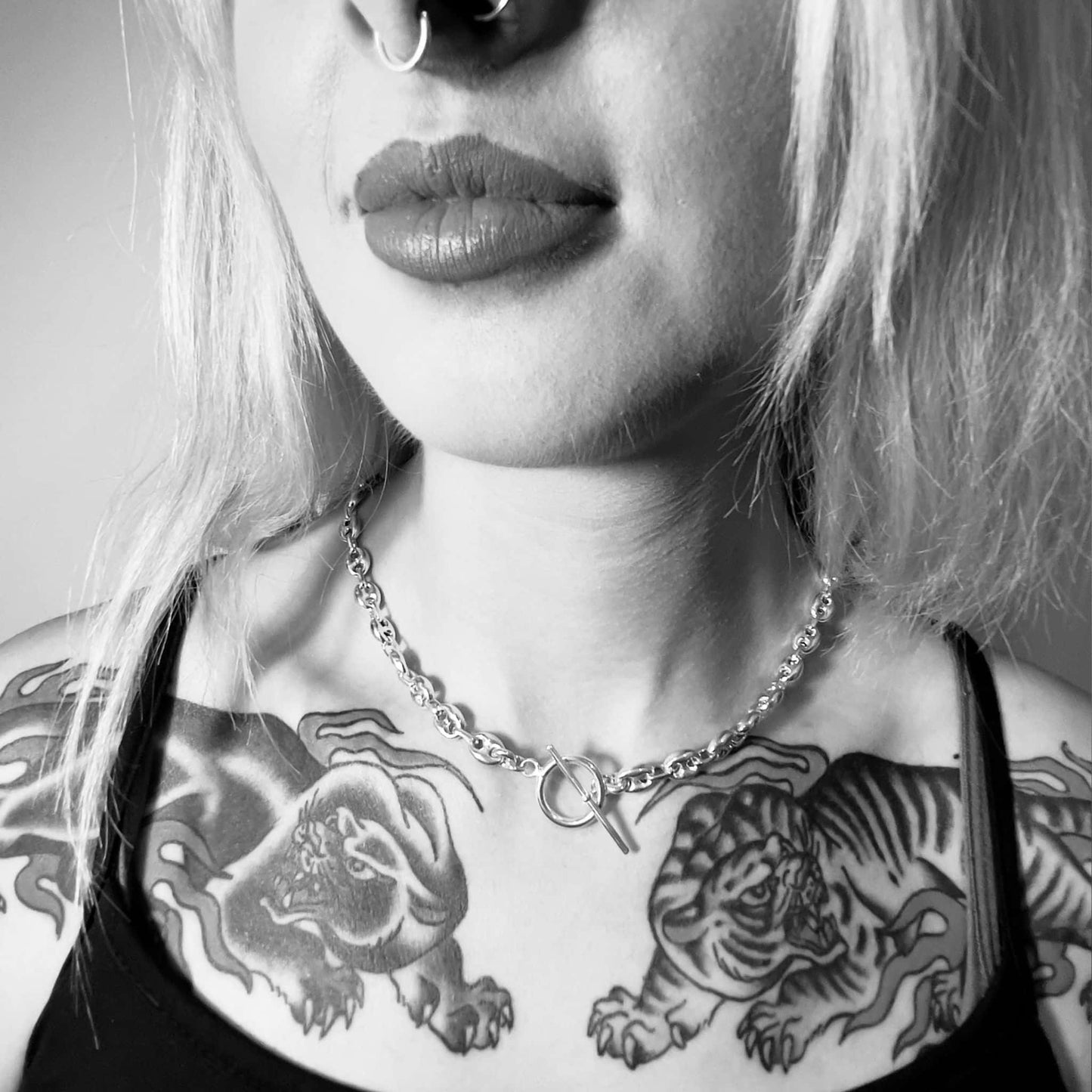 Black and white photo of a person with tattoos on their neck and shoulders wearing the DEFIANCE sterling silver necklace by ROCKSTAR★REFINEMENTS™