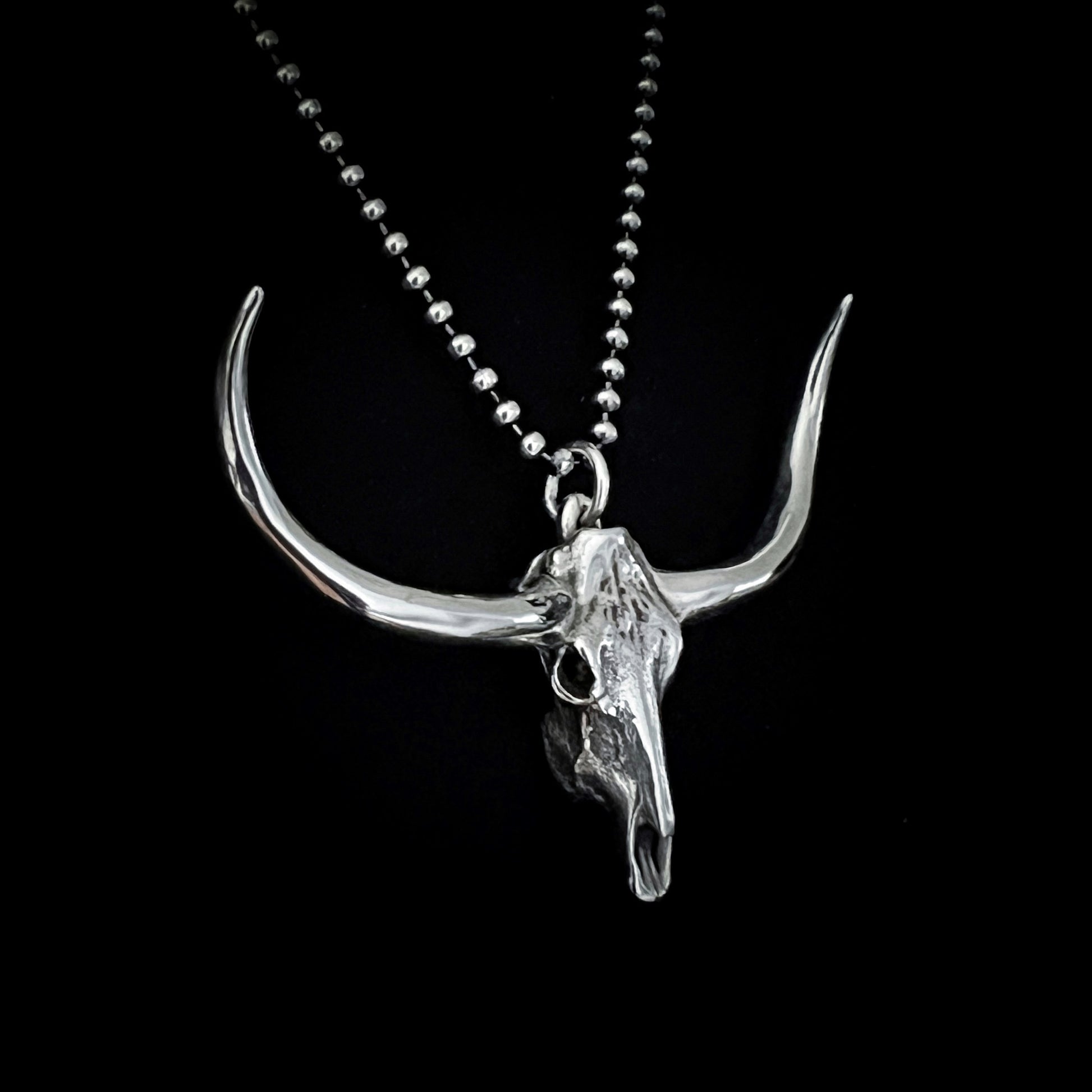 DON'T SQUAT WITH YER SPURS ON sterling silver pendant shown close-up on 24-inch oxidised ball chain, on black background