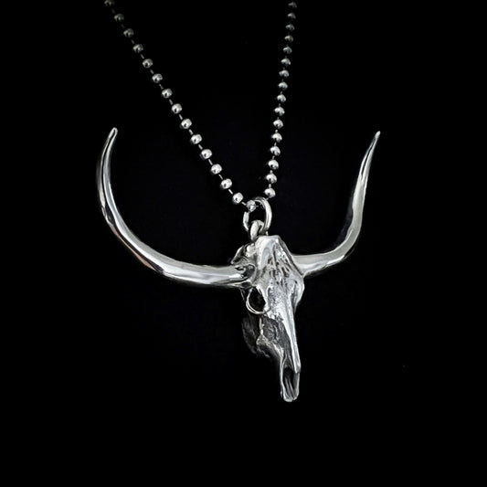 DON'T SQUAT WITH YER SPURS ON sterling silver pendant shown close-up on 24-inch oxidised ball chain, on black background