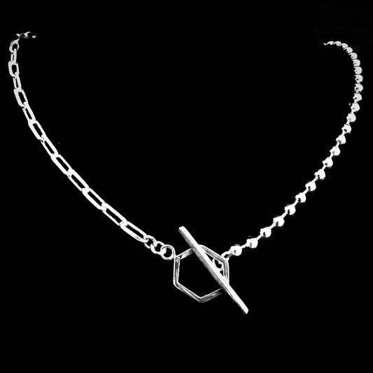 Sterling silver 'CROSSFADE' necklace combining ball chain and paperclip chain with geometric toggle clasp on black background