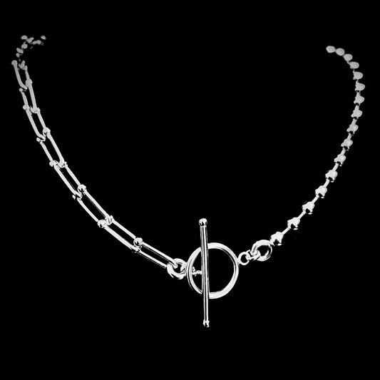 Dual chain sterling silver necklace featuring architectural links and ball chain with toggle clasp on black background