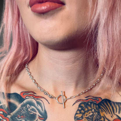 Close-up of a person with tattoos wearing the DUET necklace by ROCKSTAR★REFINEMENTS™