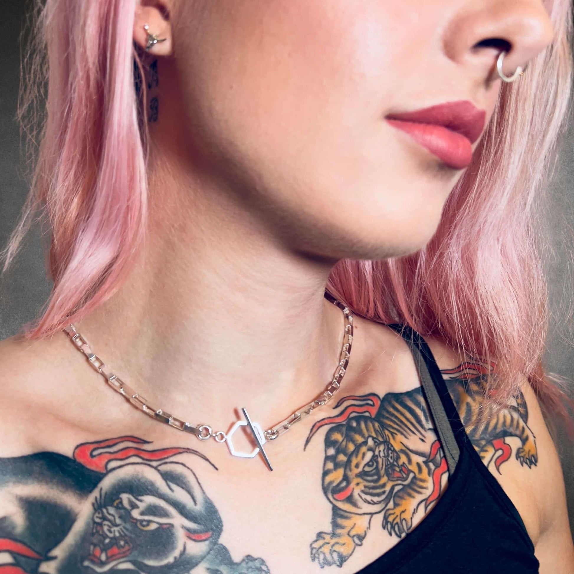 Close-up of a person with tattoos on their neck and shoulders, wearing the FULL STACK necklace by ROCKSTAR★REFINEMENTS™