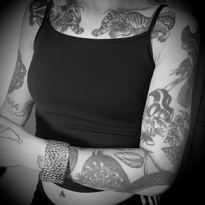Black & White photo of a person wearing a black vest top with visible tattoos on arms and chest wearing MAINSTAGE bangle by ROCKSTAR★REFINEMENTS™