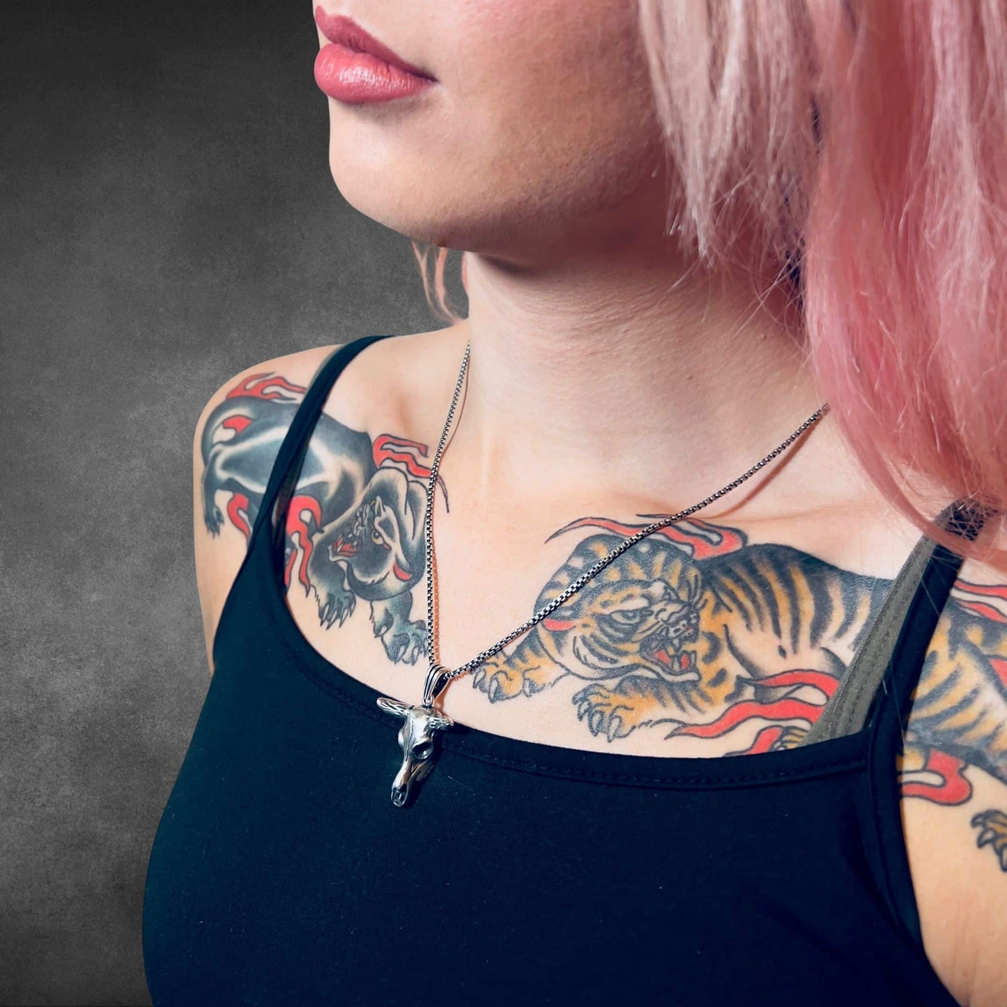 Close-up of tattooed model wearing sterling silver NO BS pendant necklace by ROCKSTAR★REFINEMENTS™ against textured grey background.