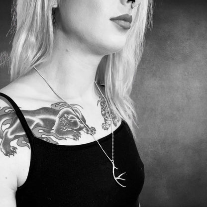 Black and white portrait of a person with tattoos on their neck and shoulders wearing NO EYE DEER sterling silver pendant on ball chain by ROCKSTAR★REFINEMENTS™