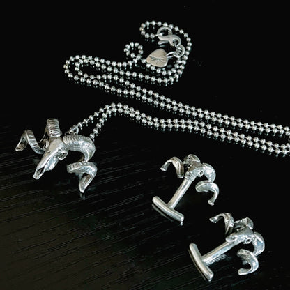 NO FLOCKS GIVEN pendant on oxidised ball chain, and FLOCKING FORMAL cufflinks photographed on a black background 
