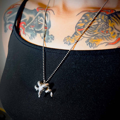 NO FLOCKS GIVEN solid silver pendant on ball chain, worn by tattooed person