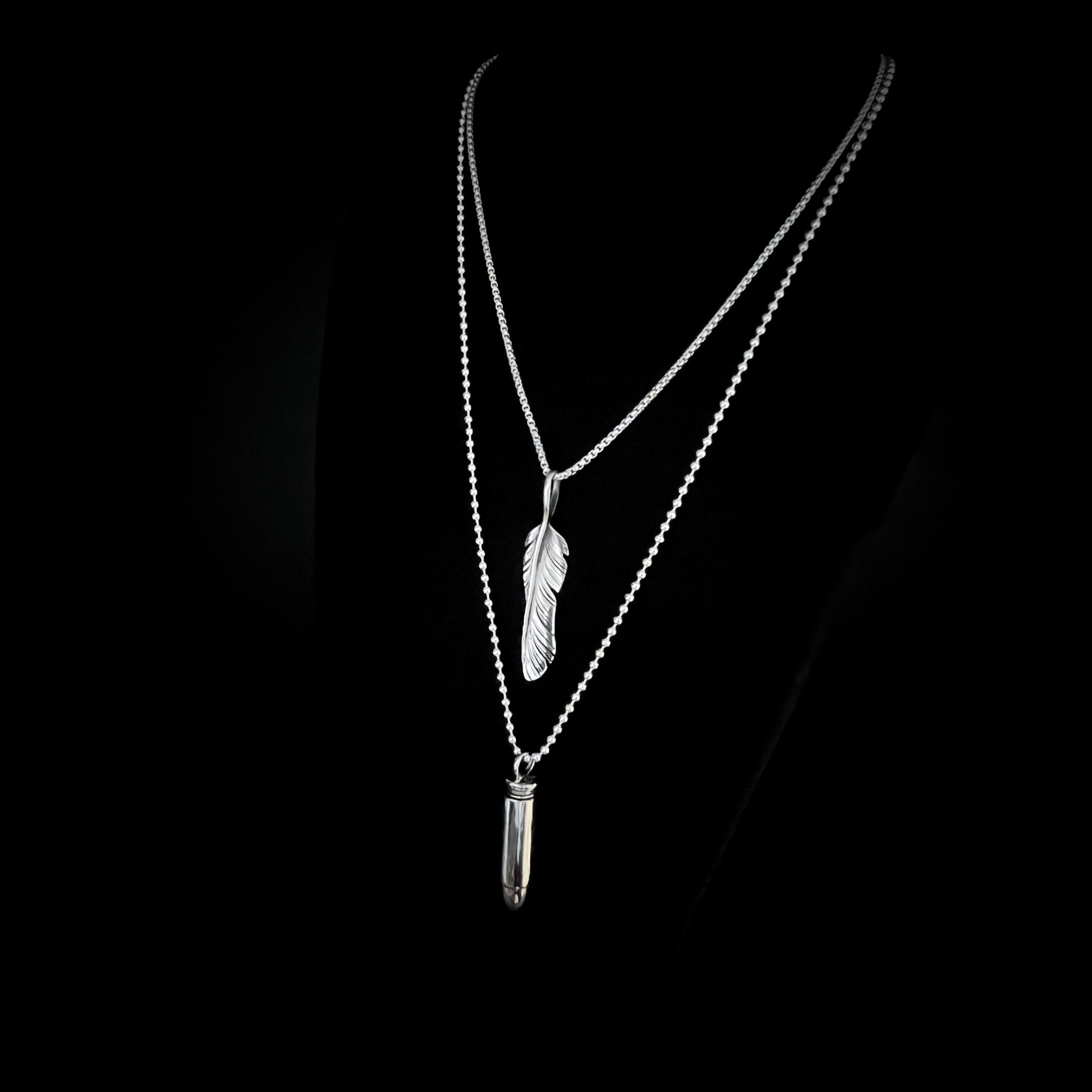 THE ONE STEP COOL KIT — sterling silver layered necklaces featuring WINGING IT on a 26-inch box chain and ONE HIT WONDER bullet pendant on a 30-inch 2.5 mm ball chain, photographed on a black background, side view, by ROCKSTAR★REFINEMENTS