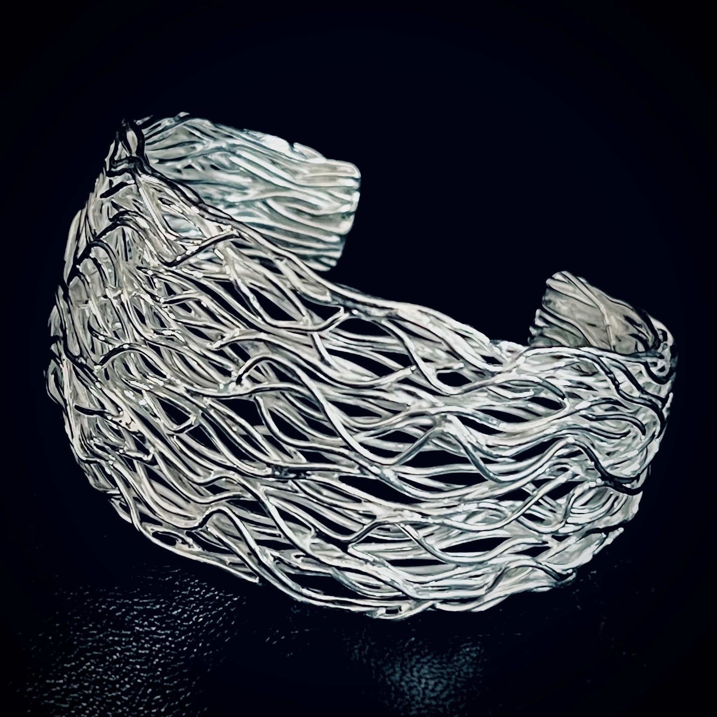 PRETTY TWISTED iconic sterling silver statement bangle by ROCKSTAR★REFINEMENTS™. Photographed close-up on a black background. 