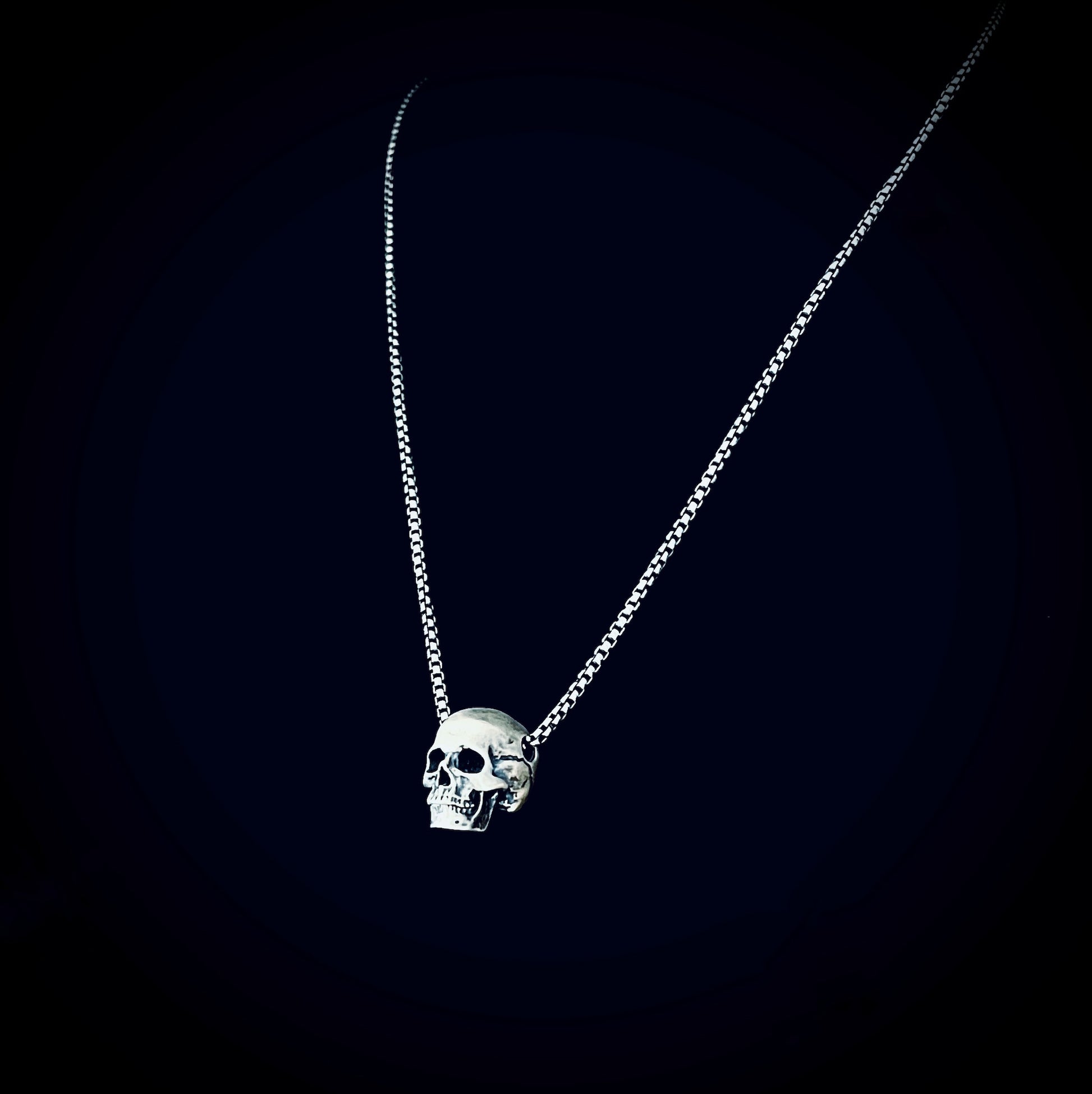 RESTING DEAD FACE — small sterling silver skull pendant necklace on a 22" box chain, photographed against a black background by ROCKSTAR★REFINEMENTS