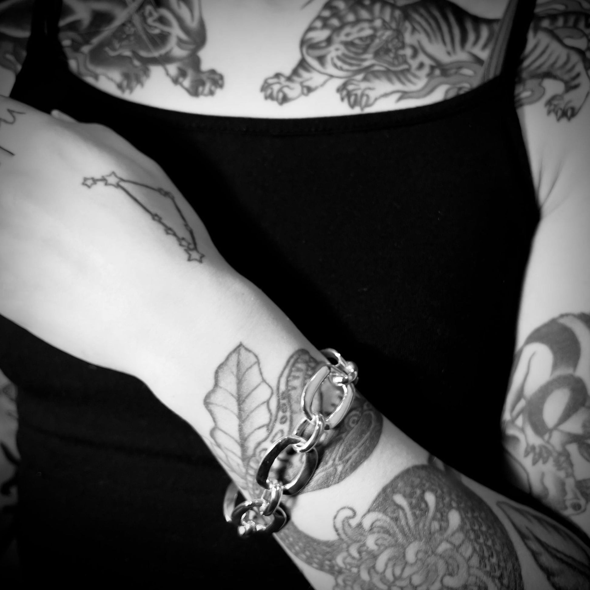 Black-and-white close-up of tattooed model wearing sterling silver SHOWSTOPPER bracelet by ROCKSTAR★REFINEMENTS™