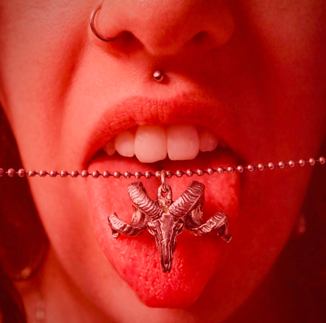 Close up of The Untamed with NO FLOCKS GIVEN sterling silver ram pendant on their tongue.