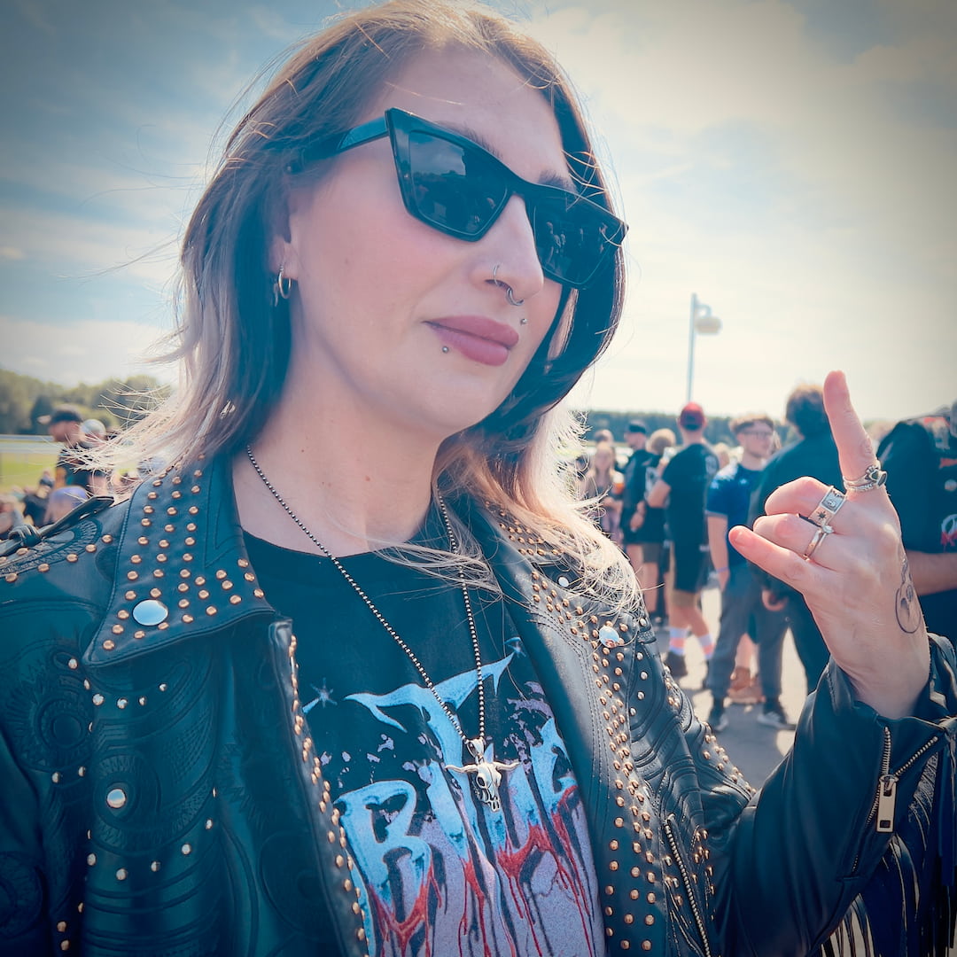 Festivalgoer wearing the ROCKSTAR★REFINEMENTS™ 'POINT OF NO RETURN' sterling silver pendant at an outdoor rock festival.