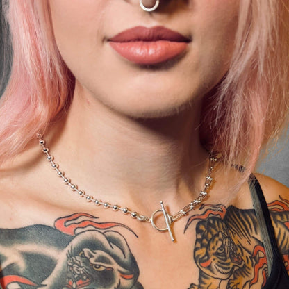 Close-up of a person with a tattooed chest wearing SYNCED sterling silver necklace by ROCKSTAR★REFINEMENTS™ 