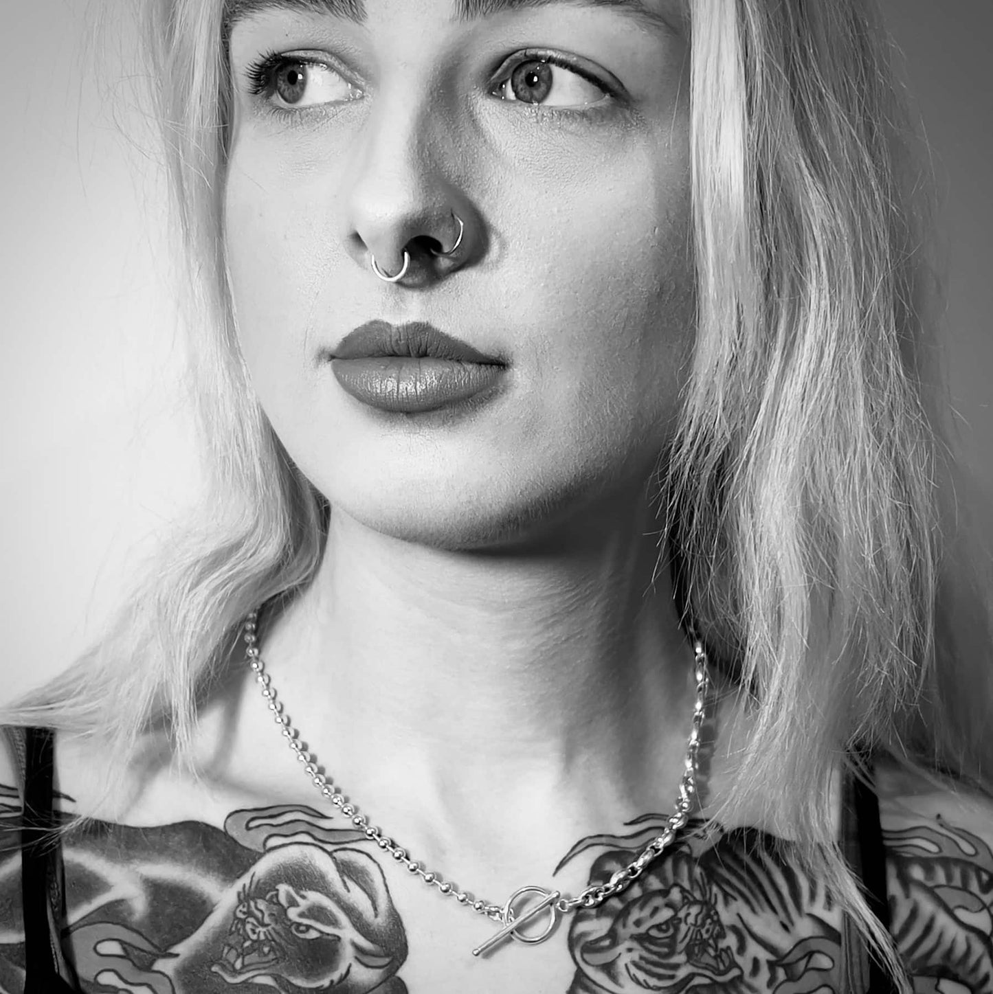 Sterling silver TRANSITION necklace by ROCKSTAR★REFINEMENTS™ worn by tattooed model in black-and-white close-up portrait.
