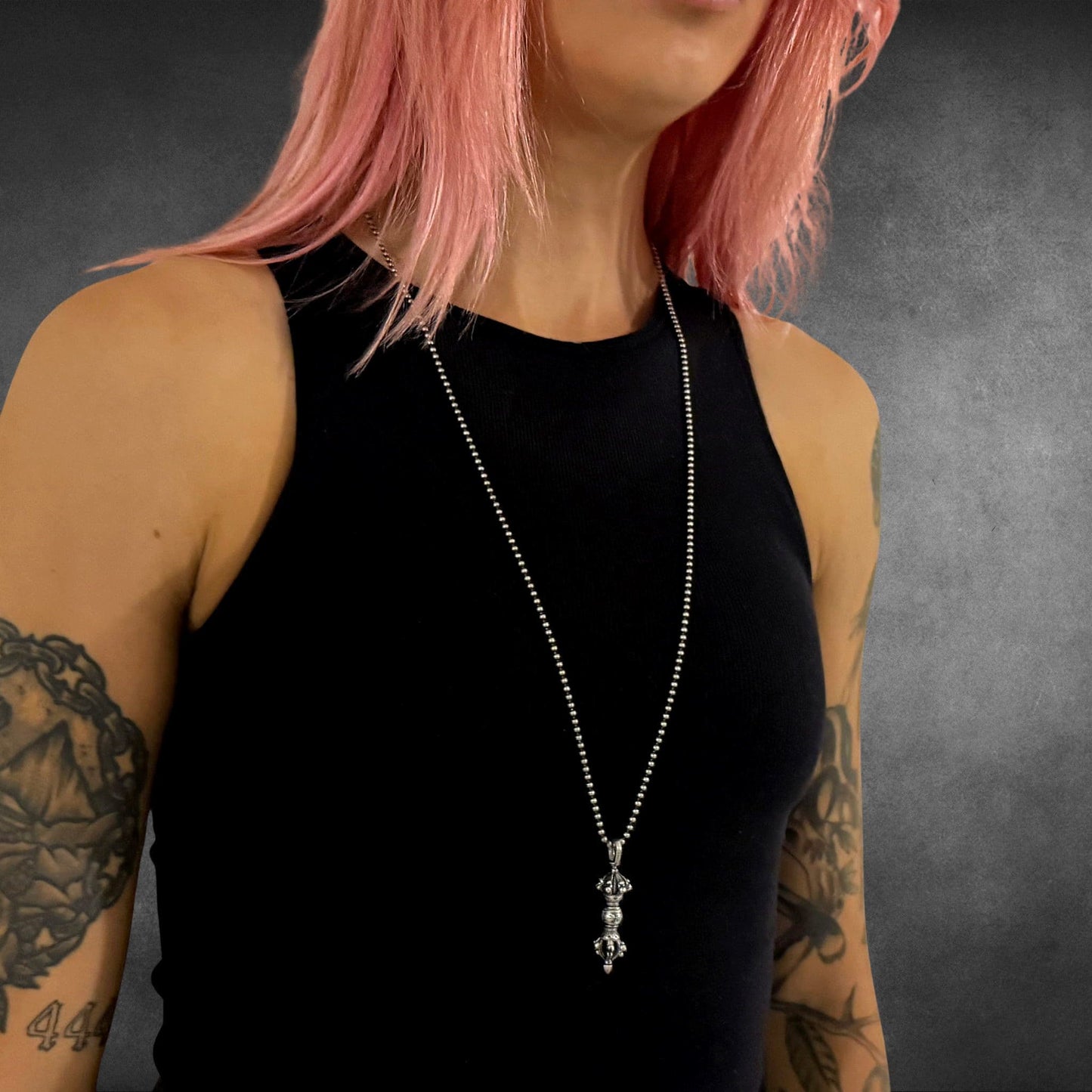 Tattooed person wearing the WARBORN RELIC on 30-inch ball chain against a dark background