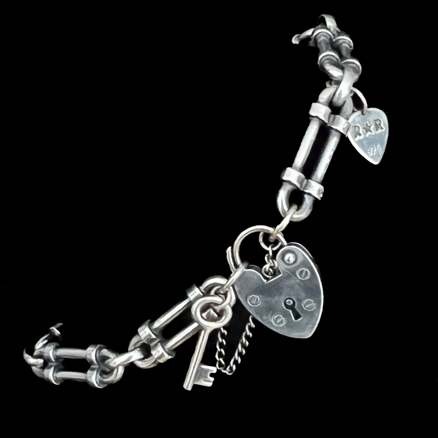 WRISTRICTED ACCESS oxidised sterling silver bracelet close-up on a plain black background.