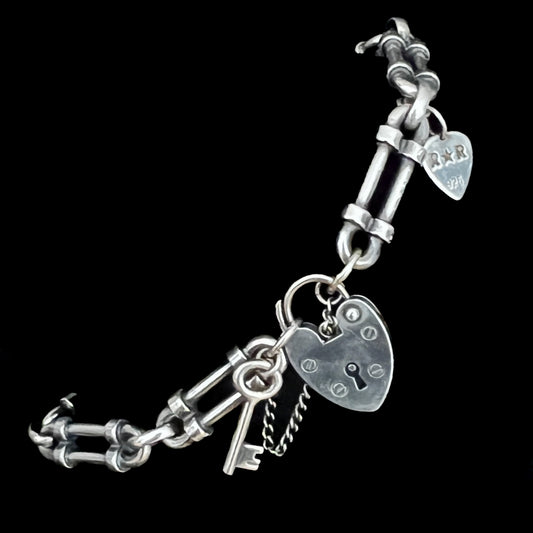 WRISTRICTED ACCESS oxidised sterling silver bracelet close-up on a plain black background.