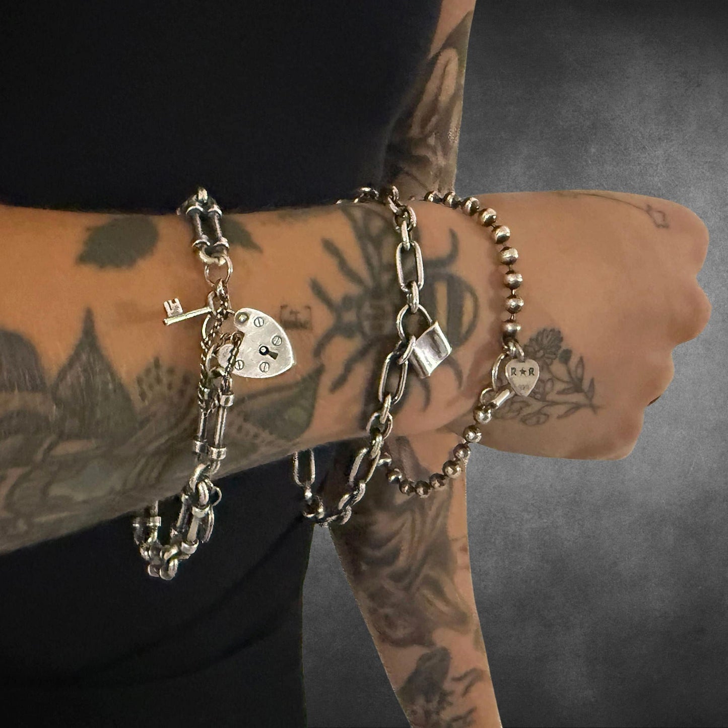 WRISTRICTED ACCESS, LOCKED-IN WRIST CHAIN, & SIDEKICK SLAYER Sterling silver bracelets worn stacked on a model.