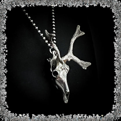 Sterling silver reindeer skull pendant on a 24 inch ball chain against a black background with a tinsel border