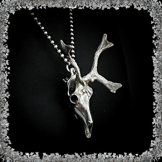 Sterling silver reindeer skull pendant on a 24 inch ball chain against a black background with a tinsel border