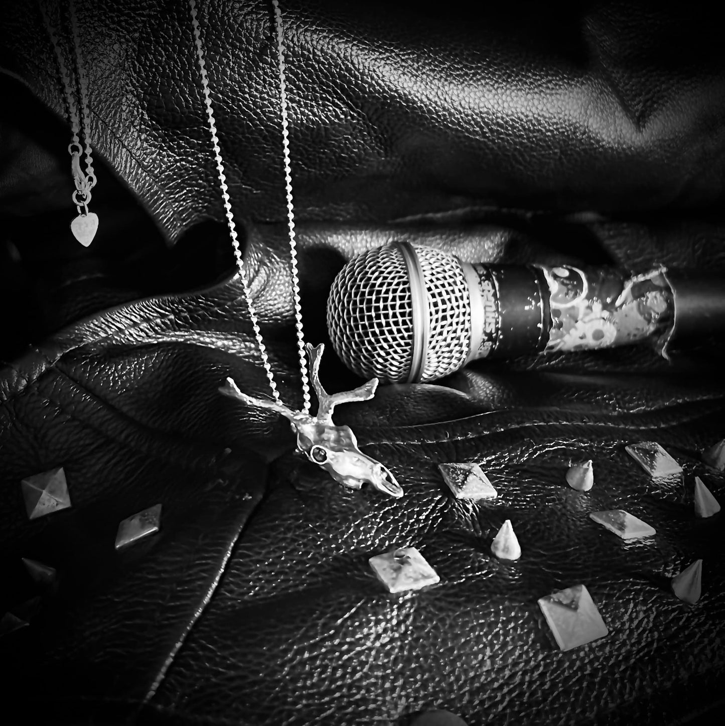 Sterling silver SLEIGHER pendant resting on stage clothes and microphone