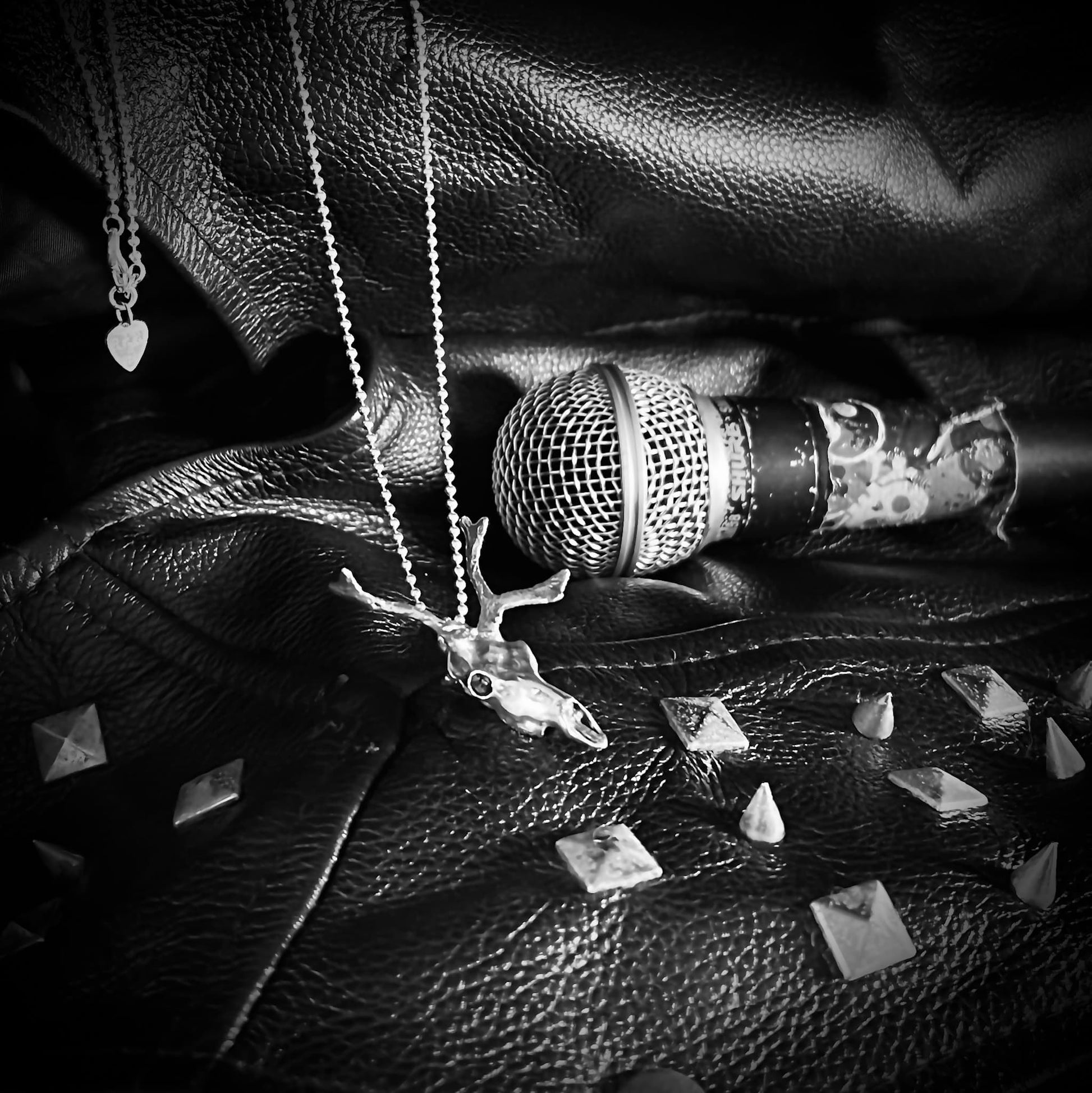 Sterling silver SLEIGHER pendant resting on stage clothes and microphone
